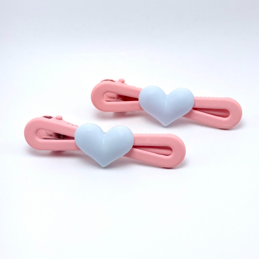 Two pink hair clips with heart-shaped ends on a white background