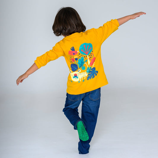Child wearing a yellow sweatshirt with colorful designs on the back, standing against a white background