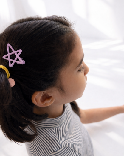 Young girl with a ponytail wearing a pink hair clip on a white background